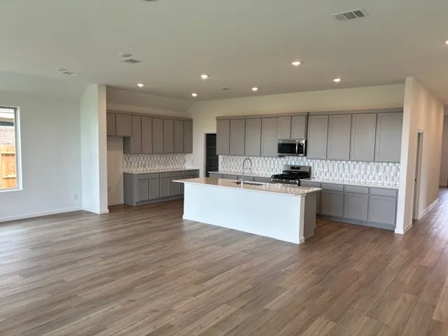a large kitchen with cabinets wooden floor and a stainless steel refrigerator