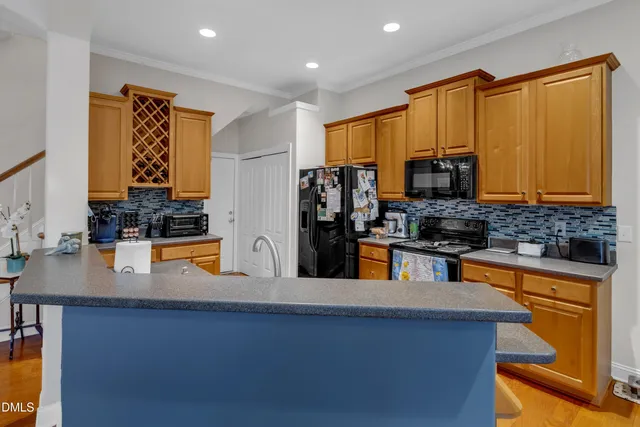 a kitchen with stainless steel appliances granite countertop a stove a refrigerator a sink a dining table and chairs with wooden floor