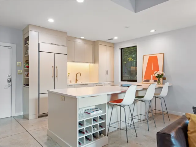 a kitchen with stainless steel appliances kitchen island granite countertop a table chairs and a refrigerator