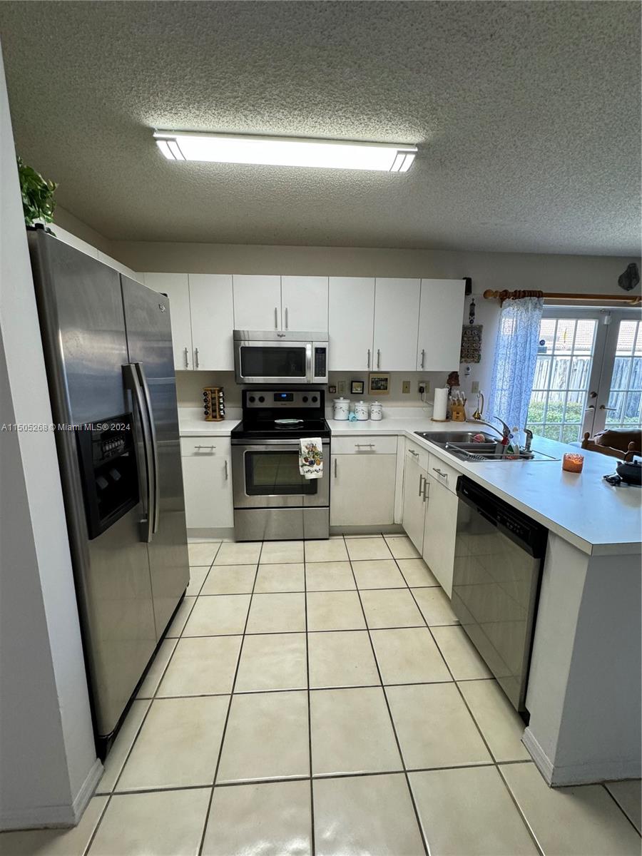 19232 Northwest 88th Place Hialeah, FL 33018 - Photo 19 of 61 a kitchen with a sink a microwave and a refrigerator