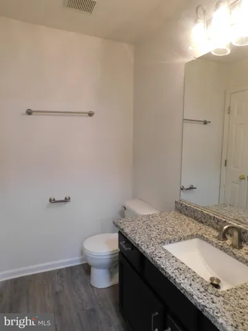 a bathroom with a granite countertop sink and a toilet