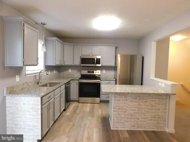 a kitchen with stainless steel appliances granite countertop a stove top oven a sink dishwasher a refrigerator and a microwave oven