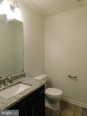 a bathroom with a granite countertop sink and a toilet