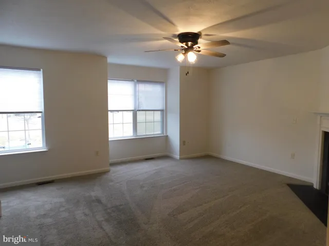an empty room with a chandelier fan and windows