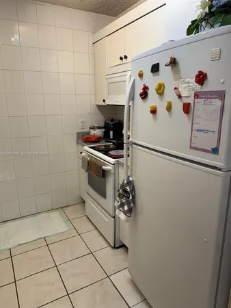 a white refrigerator freezer and a stove sitting inside of a kitchen