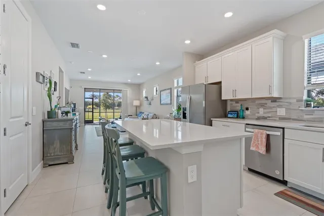 a kitchen with stainless steel appliances a table chairs refrigerator and window