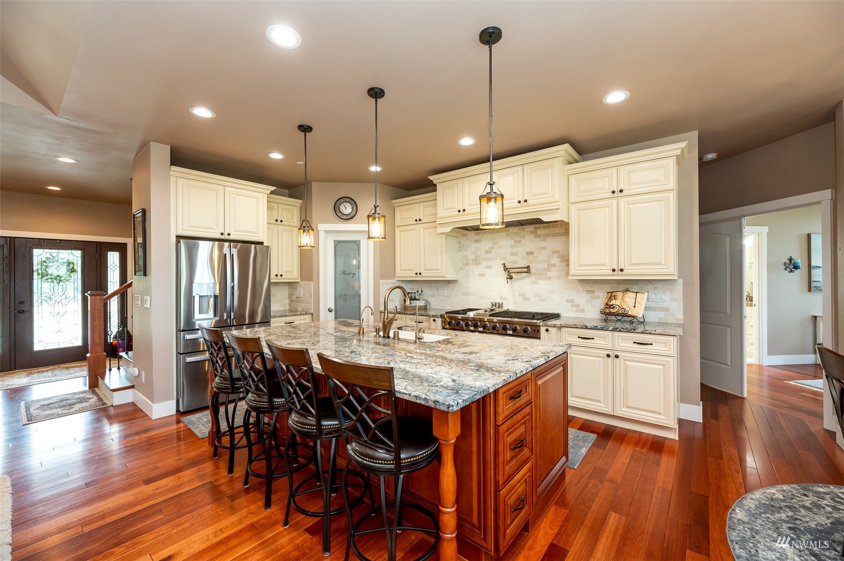 25920 80th Avenue East Graham, WA 98338 - Photo 9 of 40 a kitchen with stainless steel appliances granite countertop a stove a refrigerator a kitchen island a dining table and chairs with wooden floor