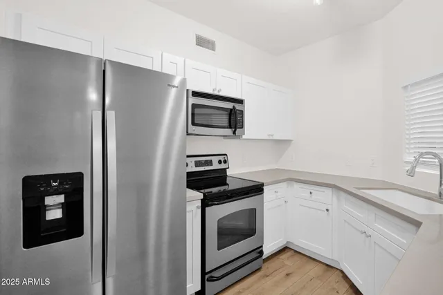 a kitchen with white cabinets and stainless steel appliances