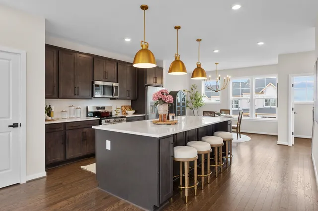 a kitchen with stainless steel appliances a stove a sink a oven a dining table and chairs