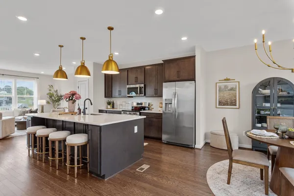 a kitchen with stainless steel appliances a dining table chairs stove and white cabinets