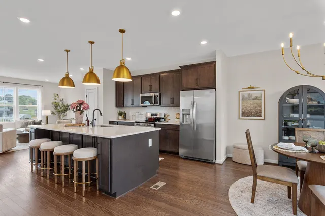 a kitchen with stainless steel appliances a dining table chairs stove and white cabinets