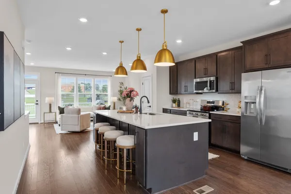 a kitchen with kitchen island granite countertop a sink a stove a refrigerator cabinets and wooden floor