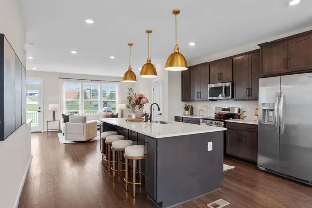 a kitchen with kitchen island granite countertop a sink a stove a refrigerator cabinets and wooden floor