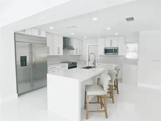 a kitchen with stainless steel appliances granite countertop a table chairs stove microwave and cabinets