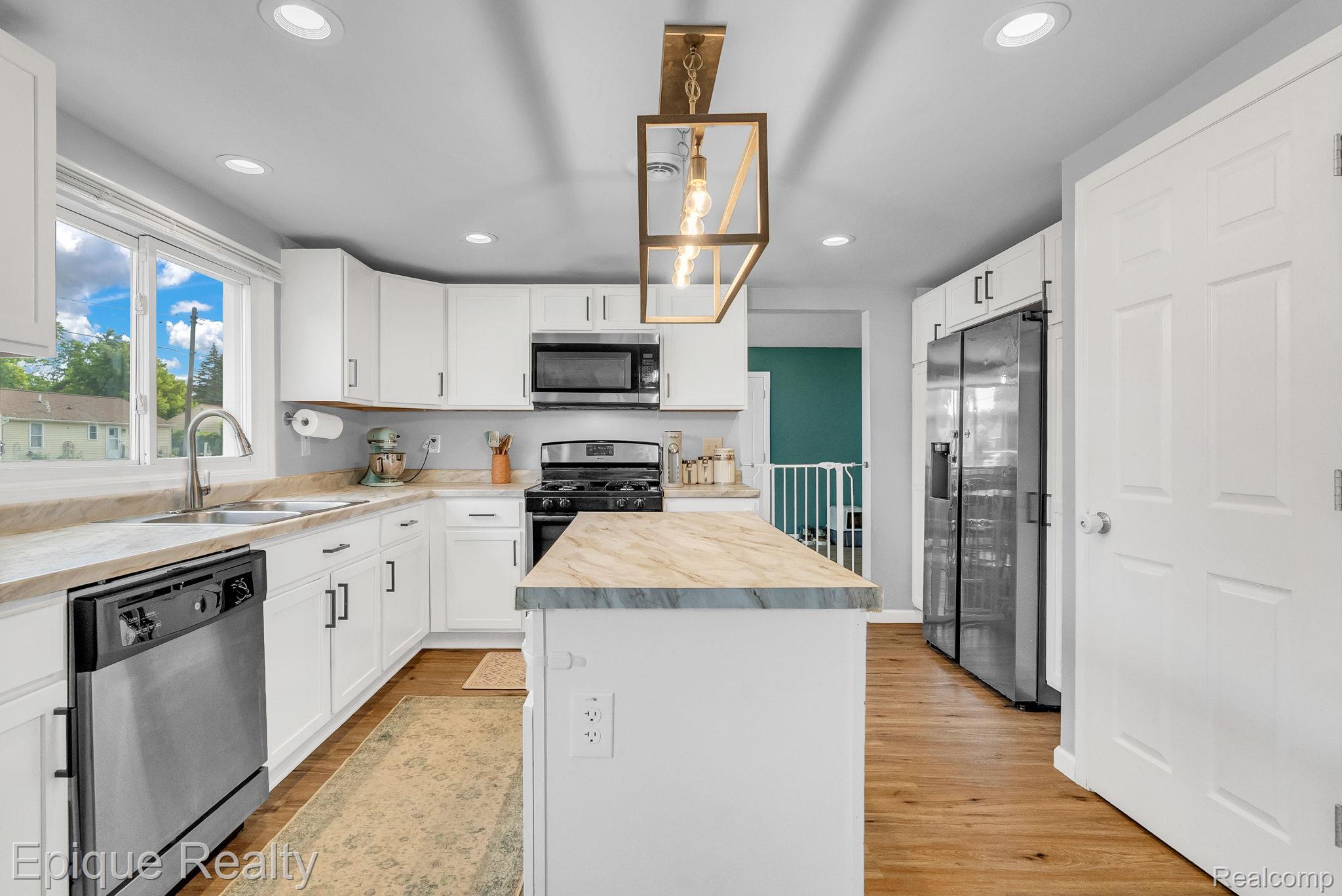 2182 North Center Road Burton, MI 48509 - Photo 10 of 34 Modern kitchen featuring white cabinetry, stainless steel appliances, an island with countertop, wood-finish flooring, and recessed lighting