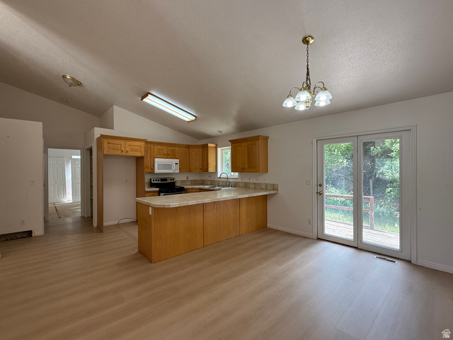 838 East Mountain Road Logan, UT 84321 - Photo 7 of 37 Eat-in kitchen featuring wood-finish cabinetry, light-toned countertops, and wood-finish flooring