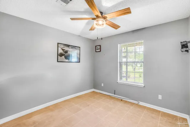 an empty room with windows and fan