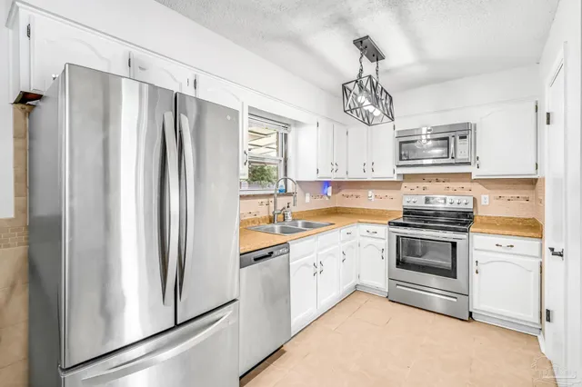 a kitchen with stainless steel appliances white cabinets and a refrigerator