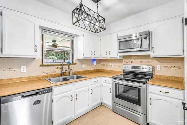 a kitchen with cabinets stainless steel appliances a sink and a window