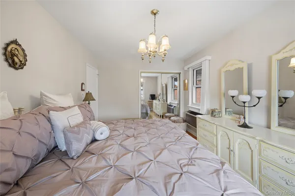 a spacious bedroom with a bed a chandelier and cabinets