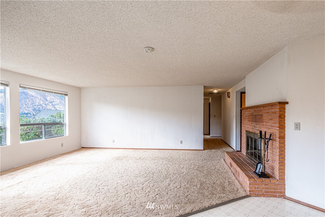 755 Wapato Way Manson, WA 98831 - Photo 13 of 40 an empty room with windows and fireplace