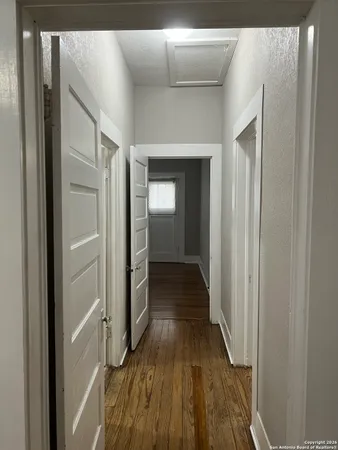 a view of a hallway with wooden floor and a bathroom