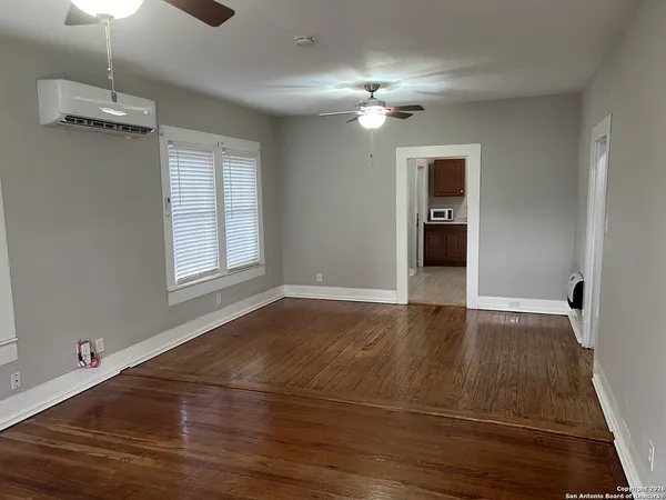 a view of empty room with wooden floor and fan