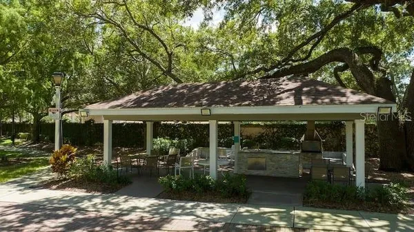 a view of a patio with table and chairs potted plants and large tree