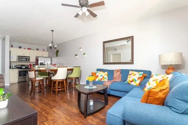 a living room with furniture kitchen view and a chandelier