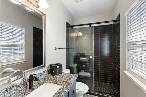 a bathroom with a granite countertop sink toilet and shower