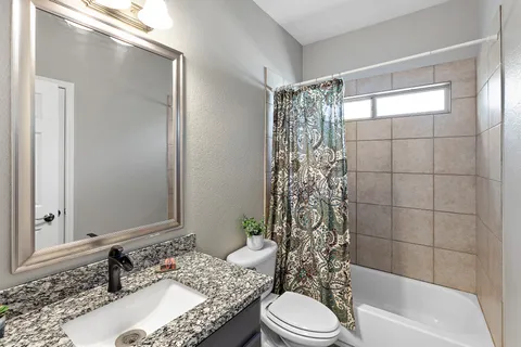 a bathroom with a granite countertop bathtub sink vanity mirror and toilet