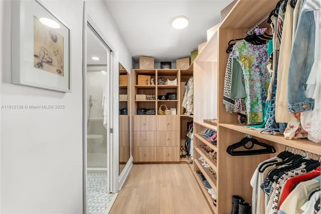 a view of walk in closet with clothes and shoes