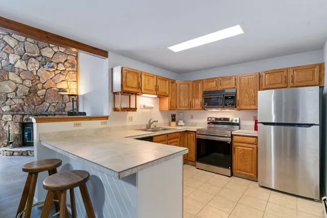 a kitchen with stainless steel appliances granite countertop a refrigerator a stove top oven a sink dishwasher and white cabinets with wooden floor