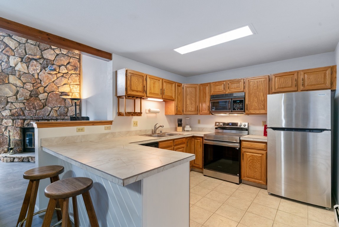 89310 Ryan Gulch Road, Unit 409 Silverthorne, CO 80498 - Photo 2 of 21 a kitchen with stainless steel appliances granite countertop a refrigerator a stove top oven a sink dishwasher and white cabinets with wooden floor