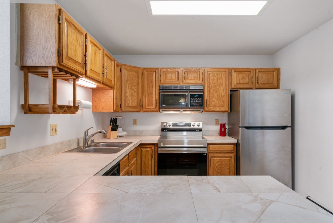 89310 Ryan Gulch Road, Unit 409 Silverthorne, CO 80498 - Photo 3 of 21 a kitchen with stainless steel appliances a refrigerator a sink a stove a microwave a sink and cabinets