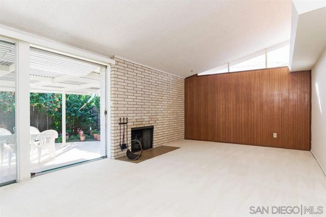 a view of an empty room with a fireplace and a window