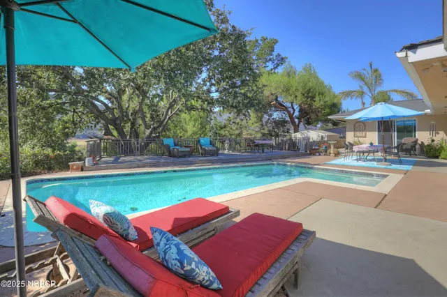 a view of a swimming pool with lawn chairs under an umbrella