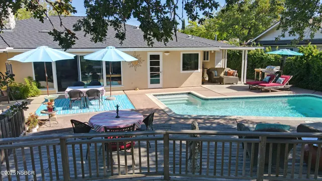 a patio with wooden floor a yard a table and chairs