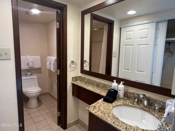 a bathroom with a granite countertop toilet sink and mirror