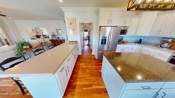 a very nice looking open kitchen with stainless steel appliances granite countertop a refrigerator a stove and a sink