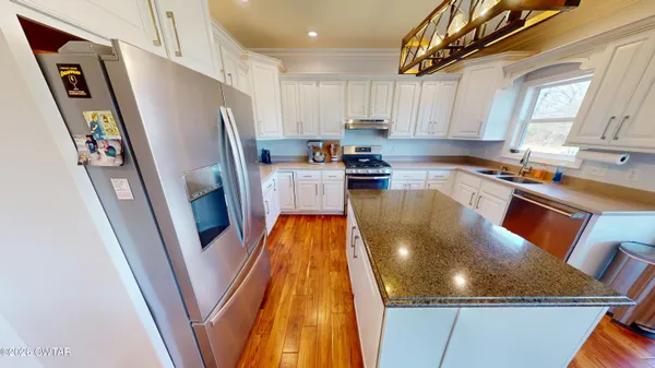 a kitchen with stainless steel appliances granite countertop a refrigerator a stove top oven a sink and dishwasher