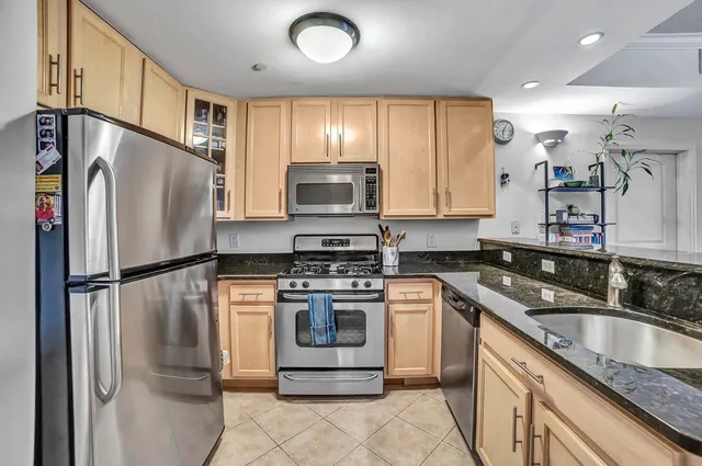 a kitchen with stainless steel appliances granite countertop a refrigerator a stove a sink and a microwave