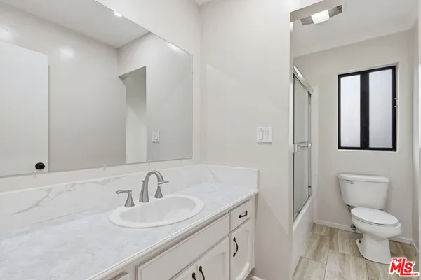 a bathroom with a toilet sink a mirror and vanity