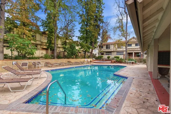 a view of a swimming pool with lawn chairs and plants