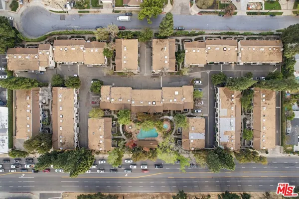 an aerial view of a residential apartment building with a yard and parking spaces
