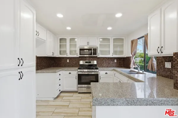 a kitchen with granite countertop a stove sink and cabinets
