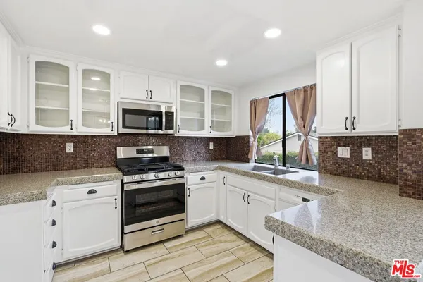 a kitchen with stainless steel appliances granite countertop a stove a sink and a microwave