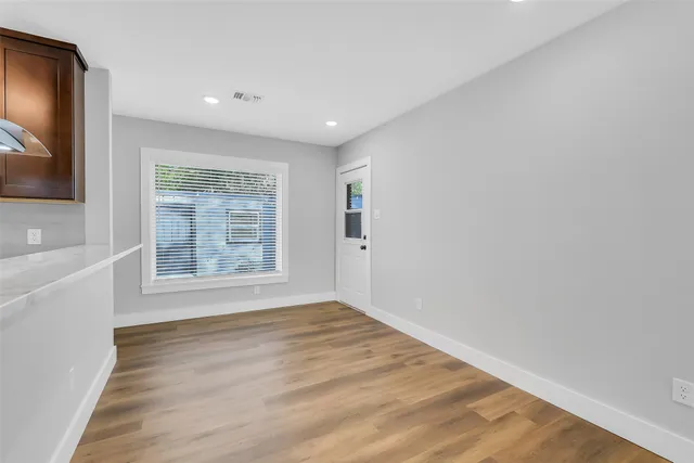 a view of an empty room with wooden floor and a window