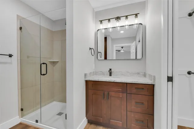 a bathroom with a toilet a sink a glass door a shower and a mirror