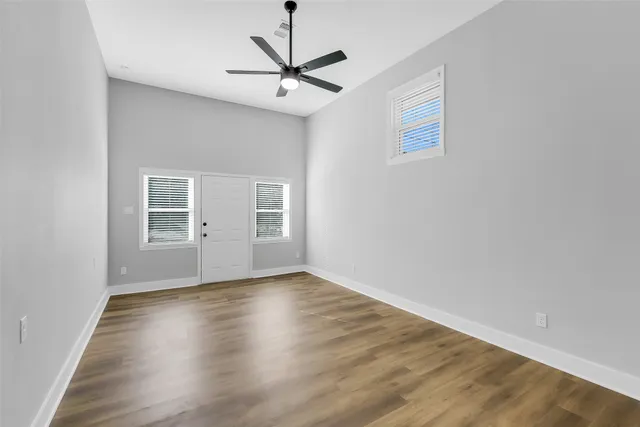 a view of an empty room with a window and wooden floor